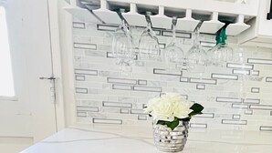 Una cocina con un enfriador de vinos integrado, un salpicadero blanco y un armario con puerta de vidrio sobre la encimera.