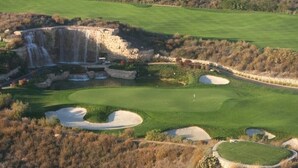 Un campo de golf con búnkeres, una cascada y un muro de piedra.