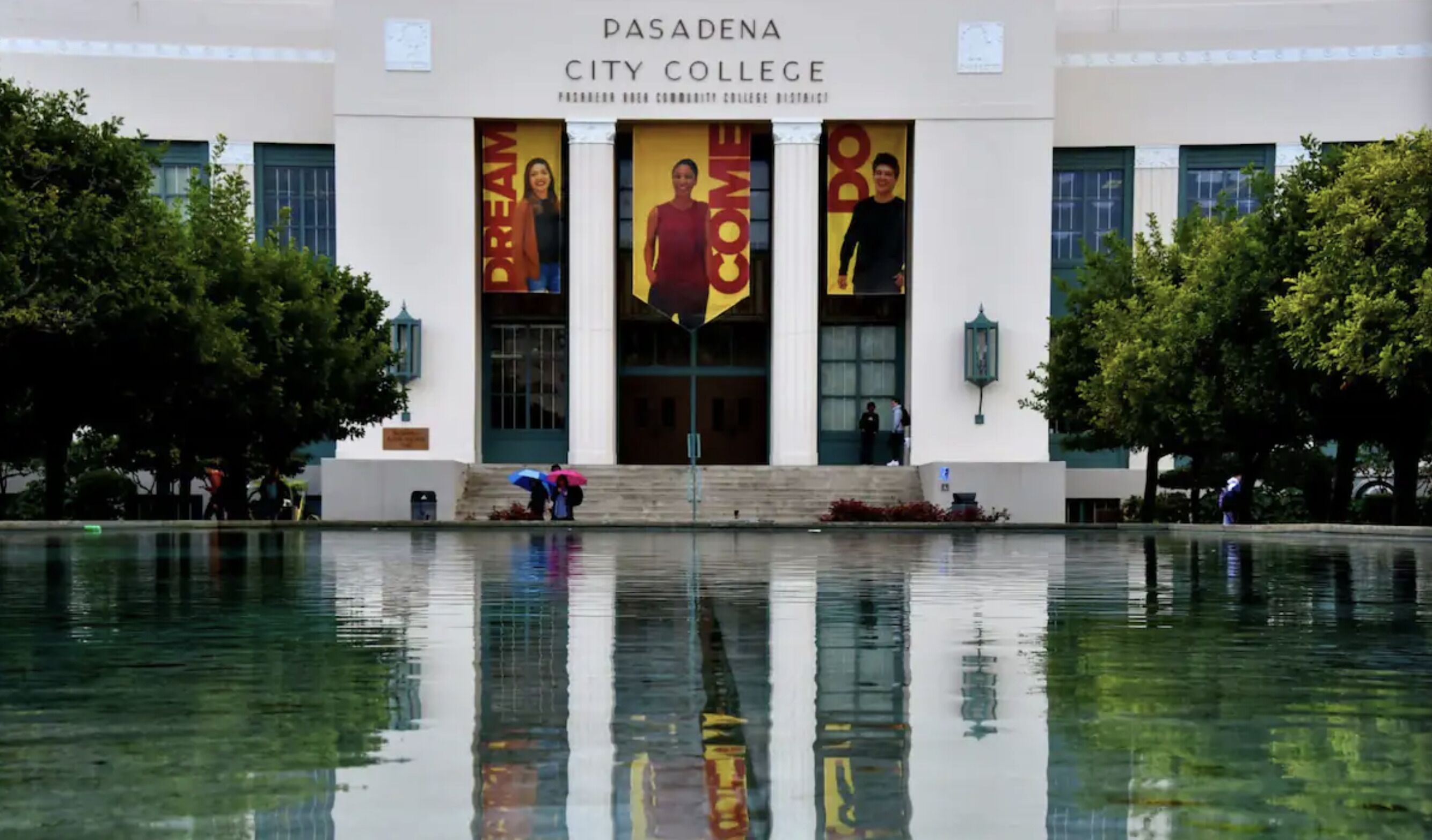 La facciata del Pasadena City College con grandi striscioni e una fontana a specchio antistante.