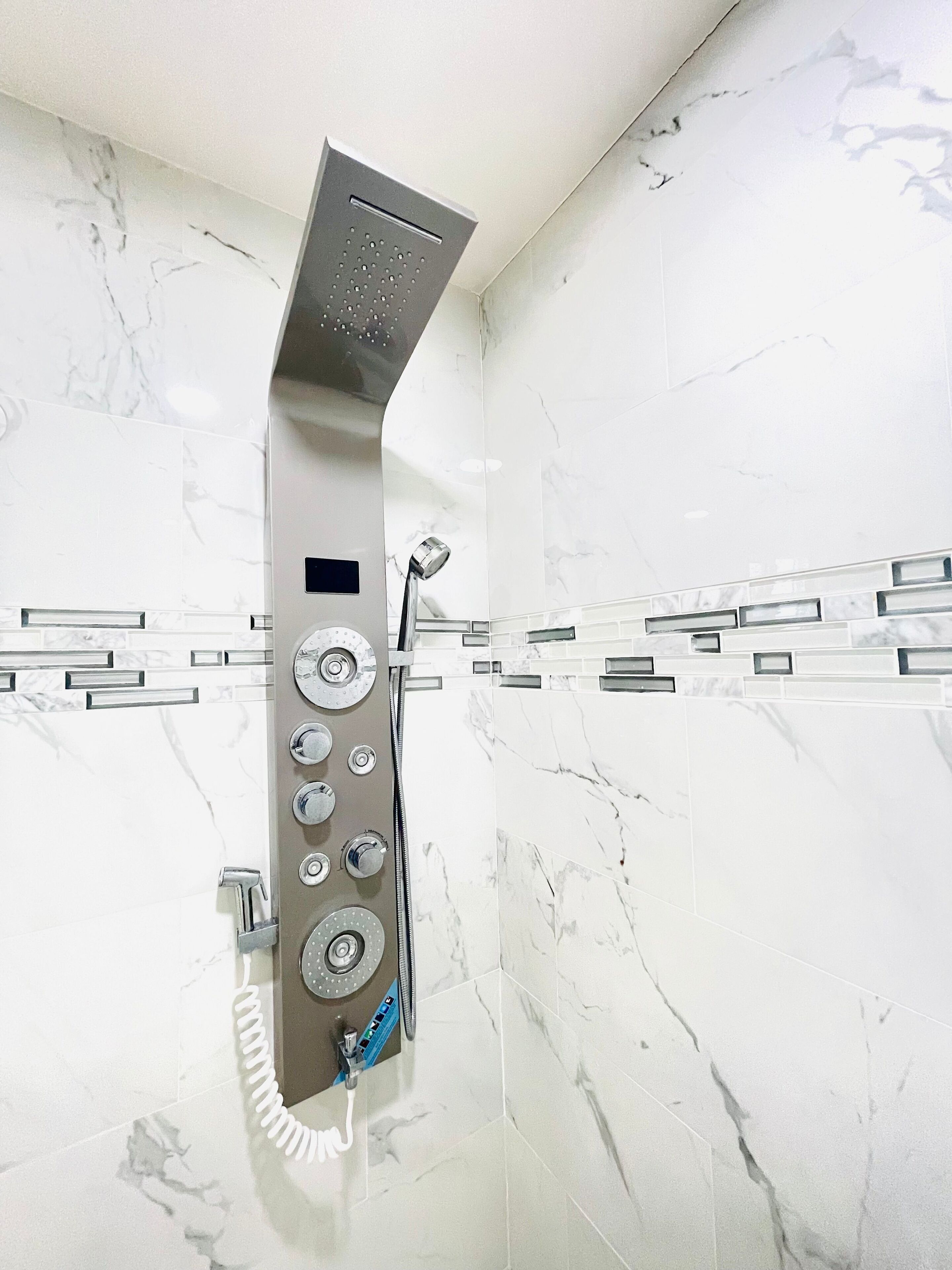 Een moderne douche met verschillende bedieningsknoppen en een handdouche.