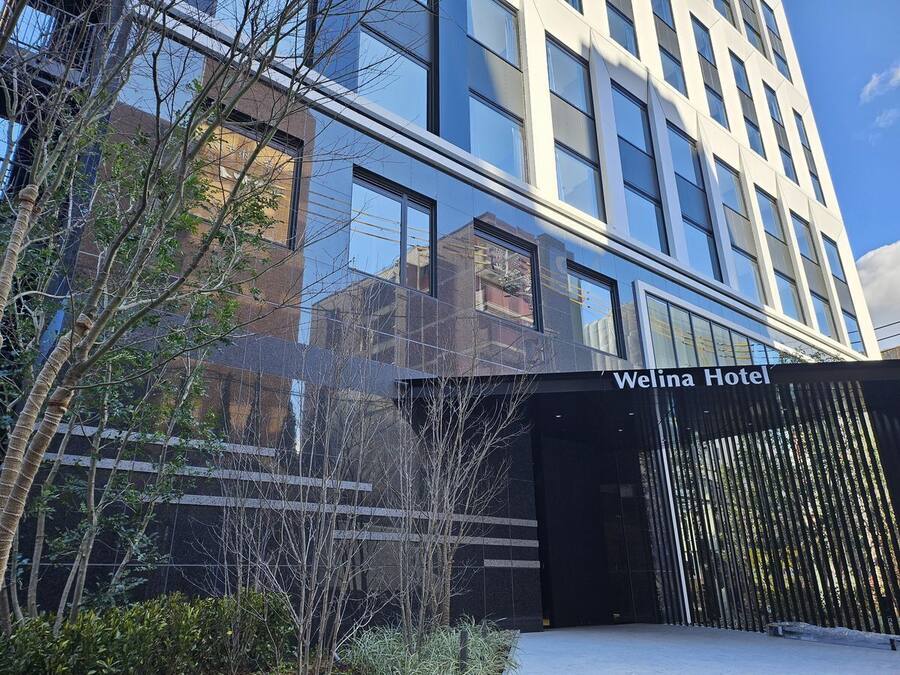 El exterior del Hotel Welina con un diseño arquitectónico moderno, que presenta grandes ventanales y fachada de vidrio reflectante.