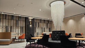 A modern conference room with a large chandelier, round tables, and black and orange chairs. - Welina Premier Osaka Namba (Osaka)