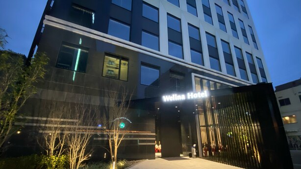 A modern hotel entrance with a glass facade, a well-lit pathway, and a sign that reads "Welina Hotel". - Welina Premier Osaka Namba (Osaka)