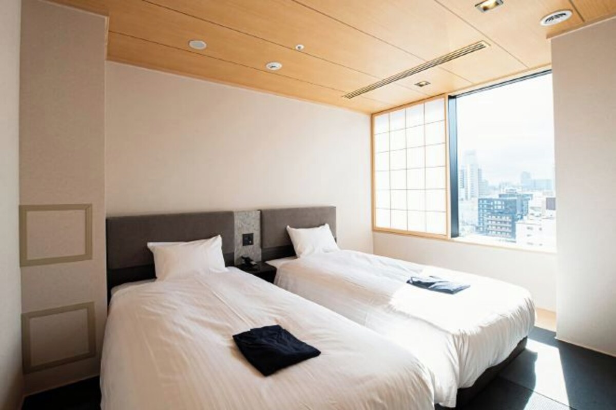 Quarto de hotel com duas camas, vista para a cidade e design moderno.