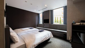 A modern hotel room with a large bed, a built-in bench, a flat-screen TV, and a view of the city. - Welina Premier Osaka Namba (Osaka)