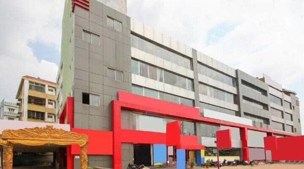 A multi-story building with a modern architectural design, featuring a prominent red facade and large windows. - Vaidh Business Hotel (Hyderabad)