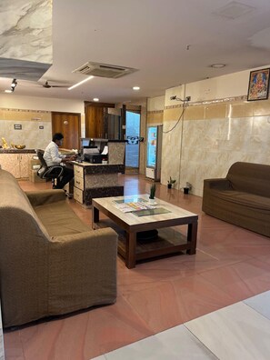 A hotel lobby with a reception desk, seating area, and a refrigerator. - Vaidh Business Hotel (Hyderabad)