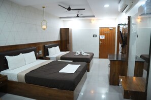 A hotel room with two beds, a wooden headboard, a desk, and a mirror. There is a ceiling fan and an air conditioning unit. - Vaidh Business Hotel (Hyderabad)