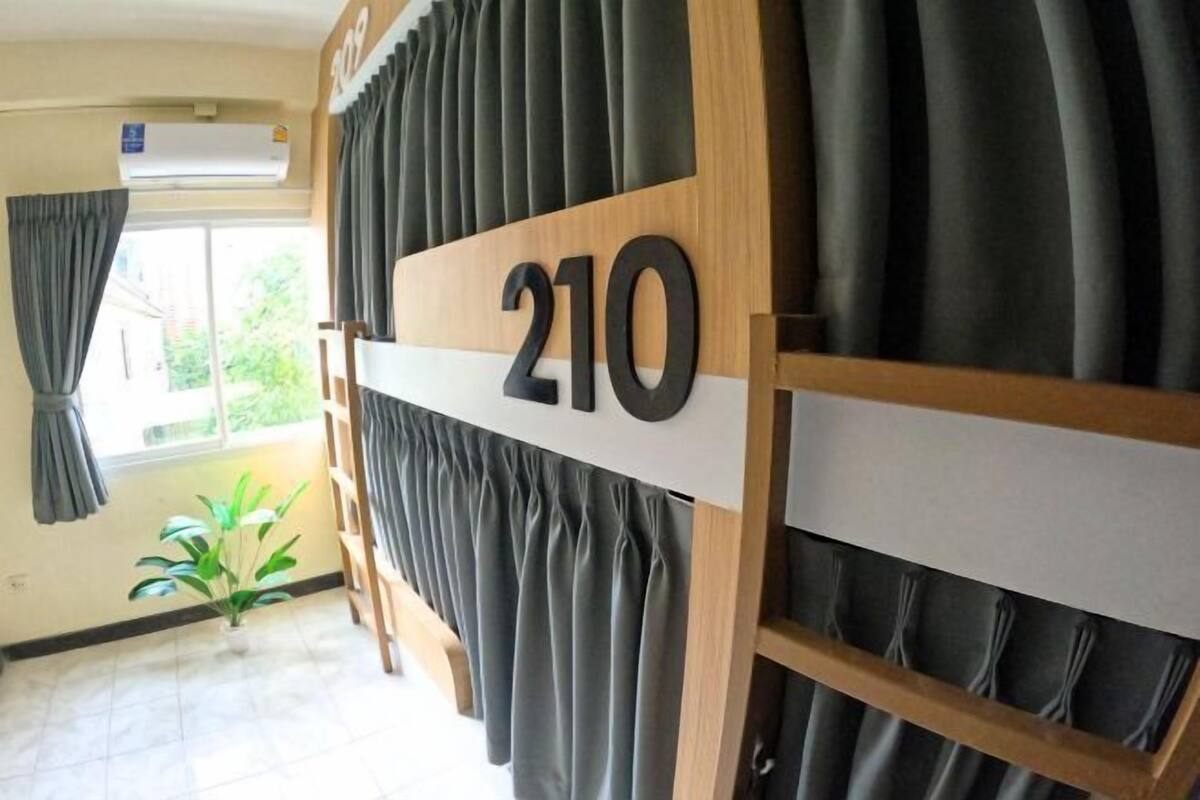 Une pièce avec un grand panneau indiquant le numéro de la porte, une fenêtre avec des rideaux et une plante en pot.
