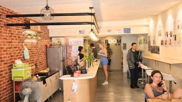 A modern kitchen with a brick wall, a wooden counter, and a hanging light fixture. - KPOP Hostel (Karon)