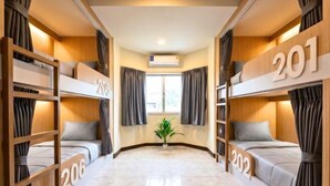A hotel room with bunk beds numbered 201, 202, 205, and 206, a potted plant, and an air conditioning unit. - KPOP Hostel (Karon)