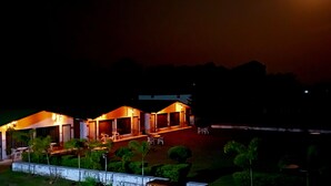 A hotel with two connected buildings, outdoor seating, and a well-maintained garden. - Six Seasons Resort (Kaladhungi)