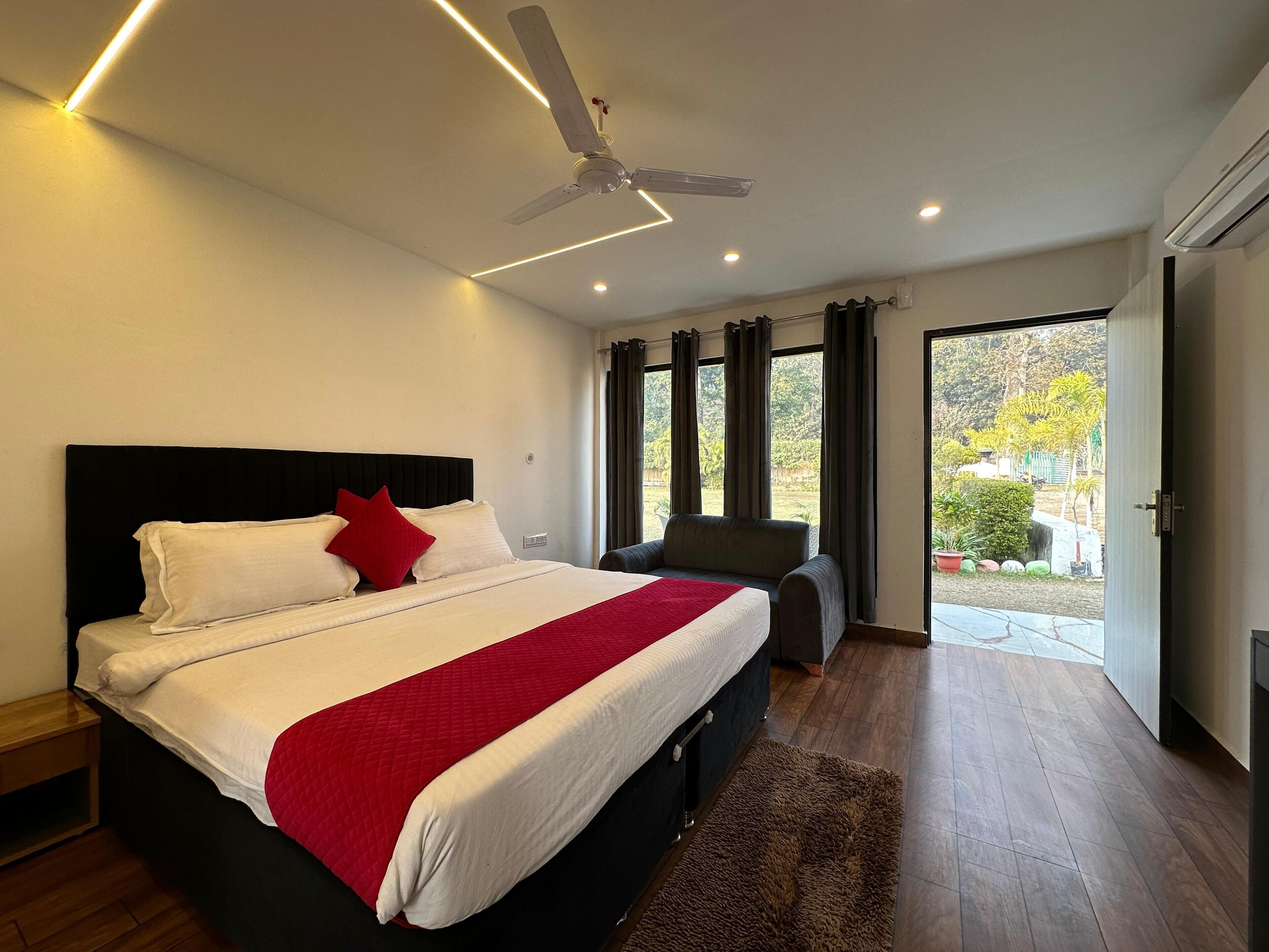 A modern bedroom with a large bed, a ceiling fan, and a view of the outdoors through large windows.