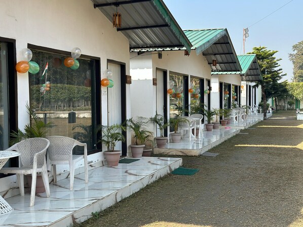 A hotel exterior with outdoor seating, potted plants, and a clear view of the surrounding area. - Six Seasons Resort (Kaladhungi)