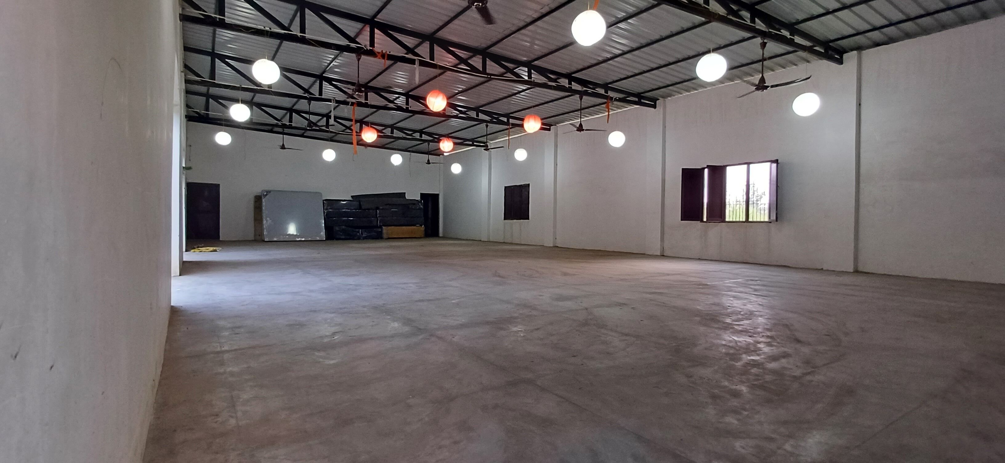 A spacious industrial-style room with a high ceiling, exposed beams, and multiple ceiling lights.