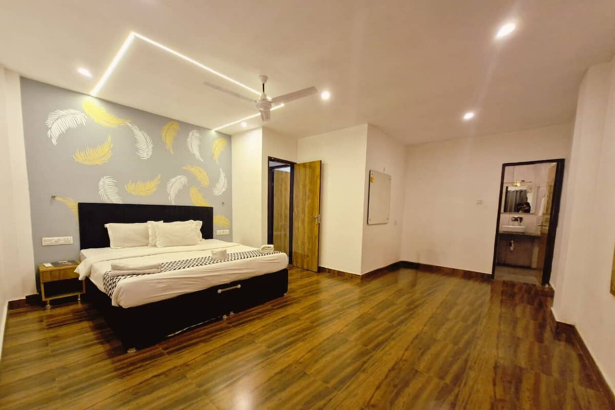 Une chambre spacieuse avec un grand lit, un plancher en bois et un ventilateur de plafond.