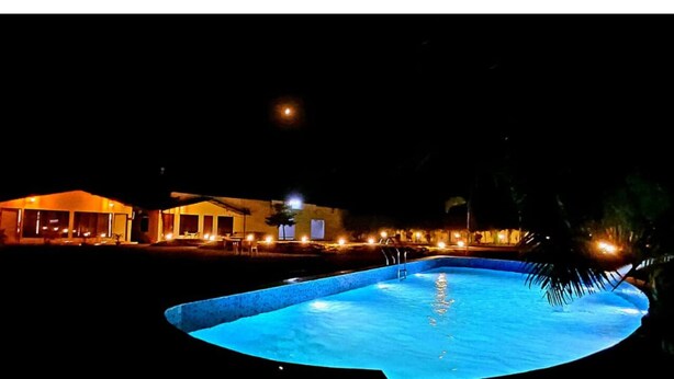 A nighttime view of a swimming pool area with a building in the background. - Six Seasons Resort (Kaladhungi)