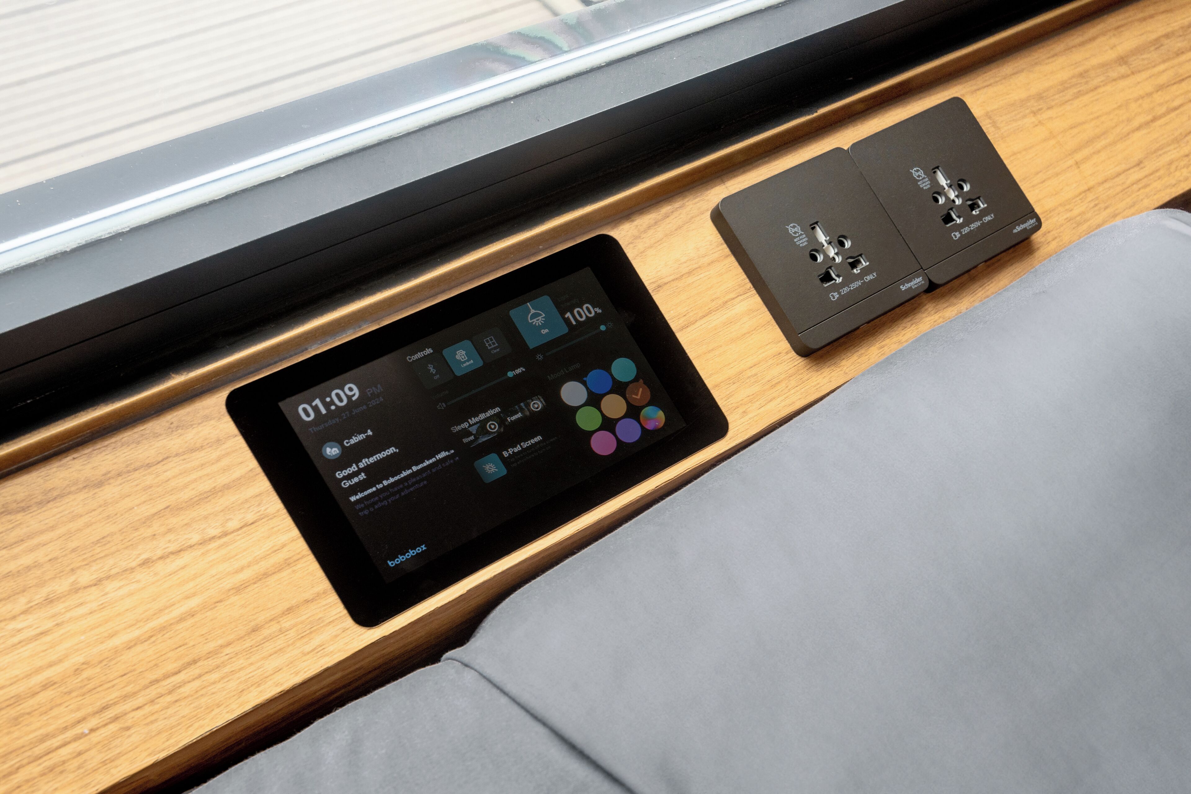 A tablet displaying a control interface, a power strip, and a cushioned bench.