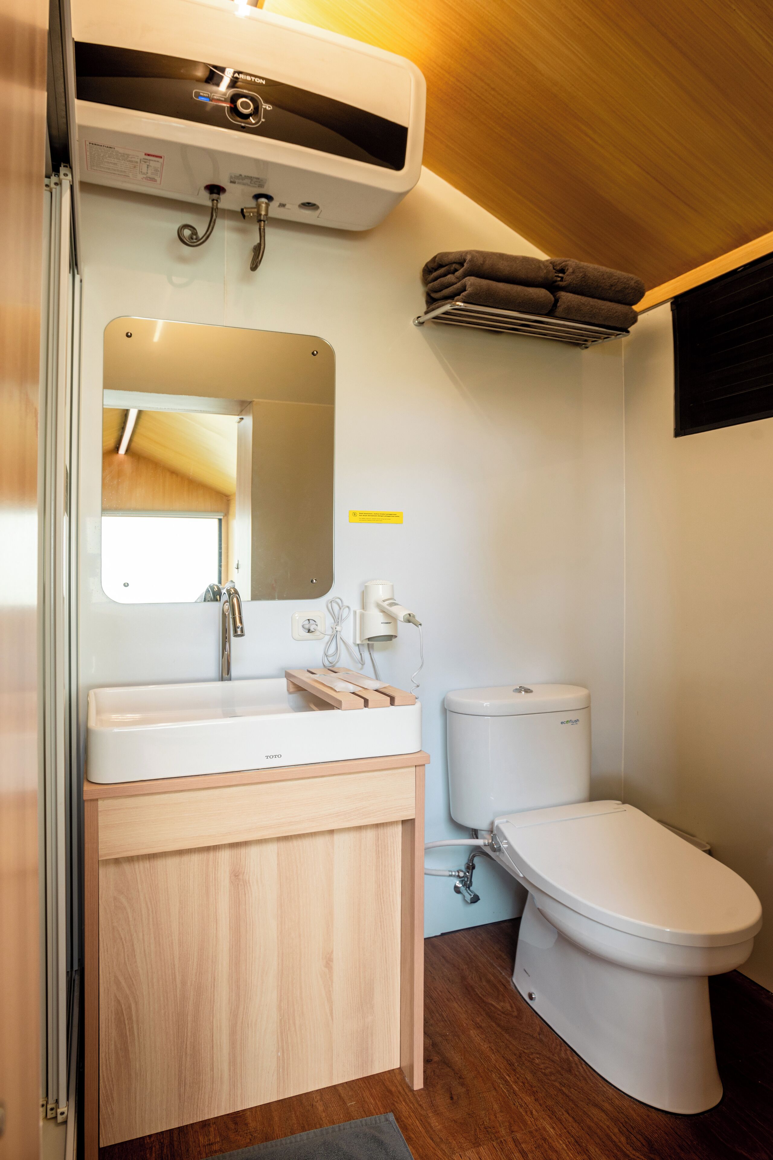 A compact bathroom with a white sink, mirror, and toilet.