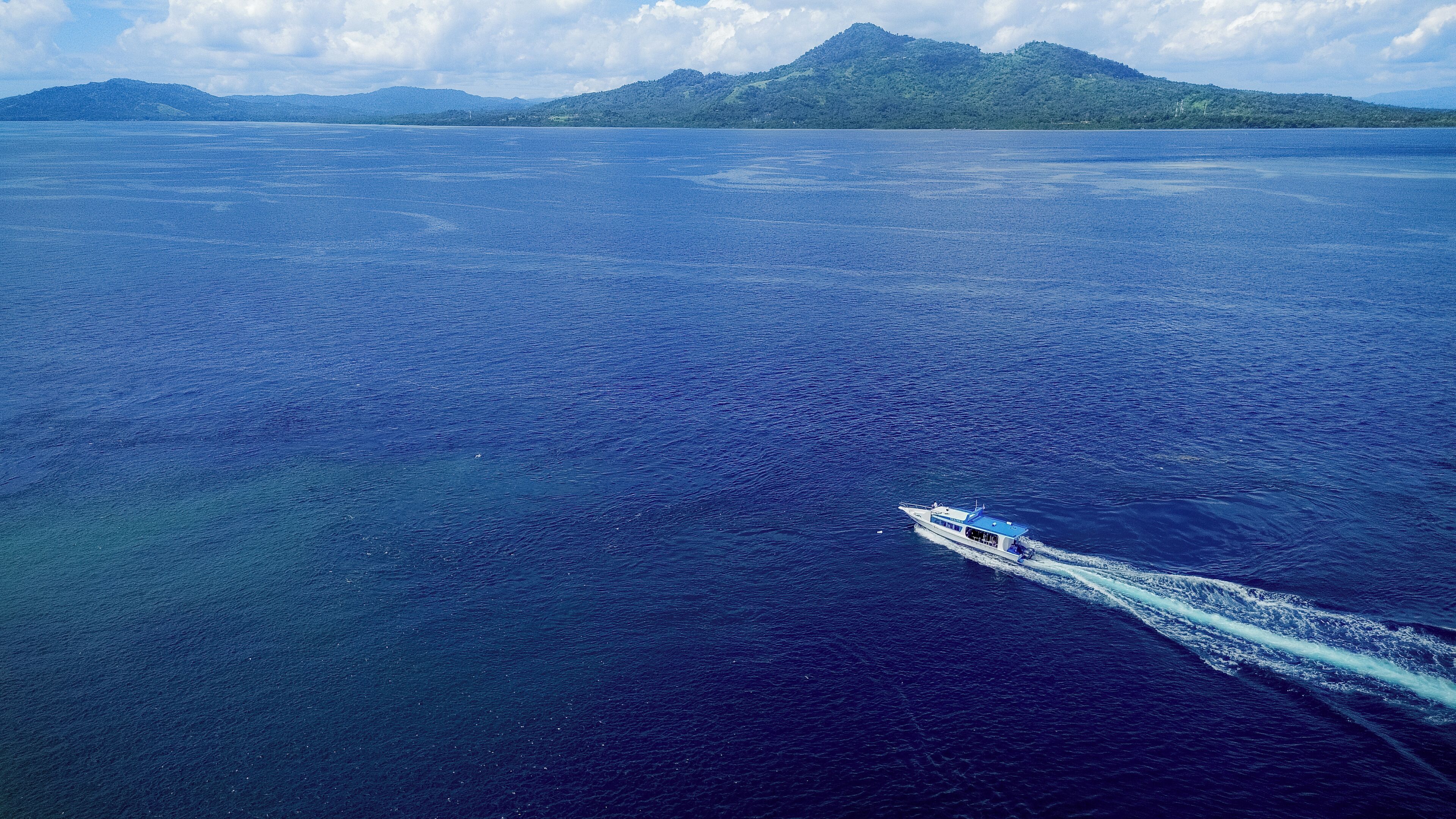 A boat on a large body of water with a mountainous landscape in the background.