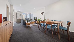 Een moderne woonkamer met een eethoek, voorzien van een bank, stoelen, een salontafel en een televisie.