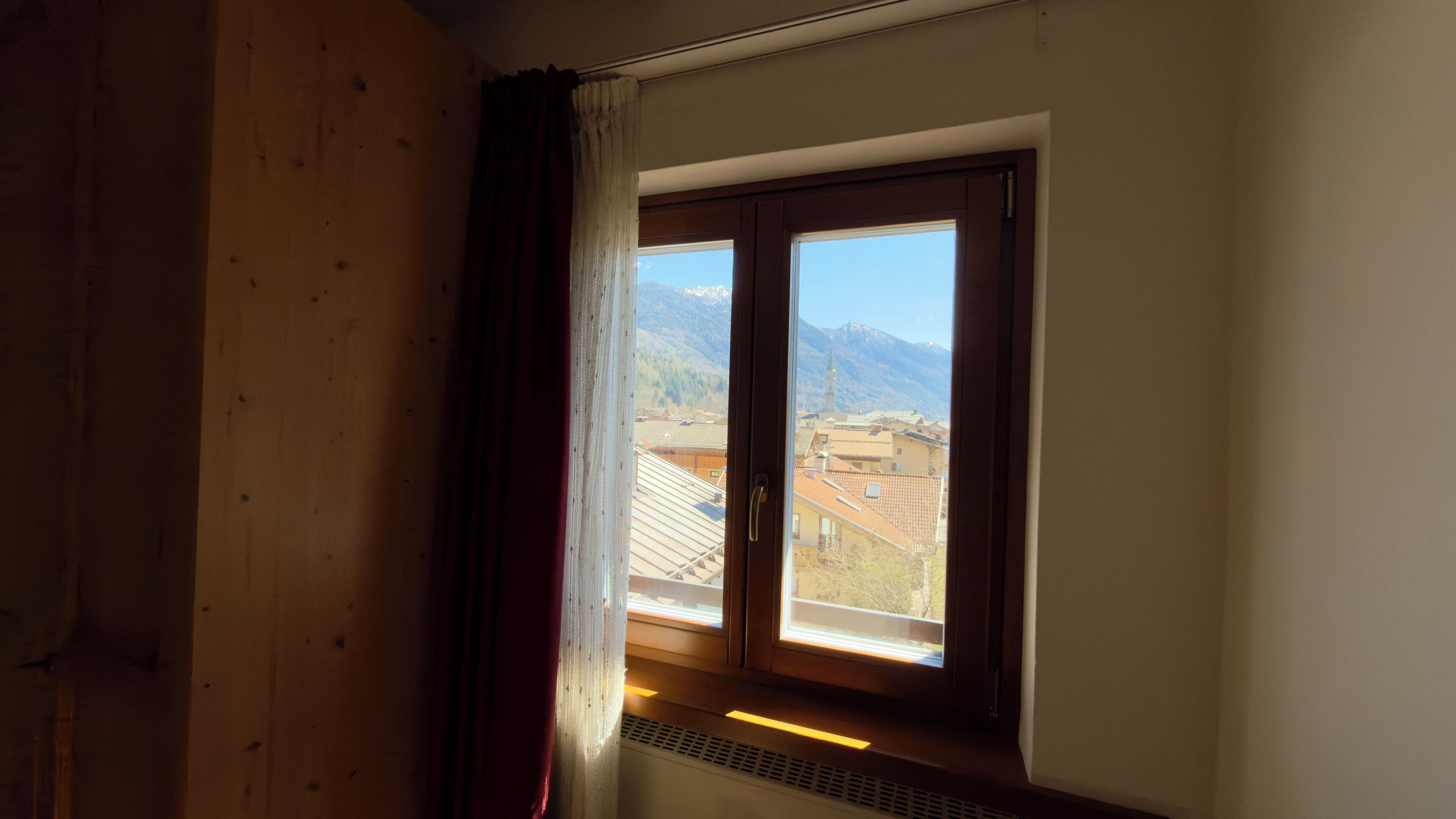 A room with a window overlooking a mountainous landscape.
