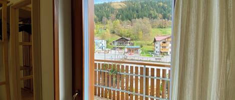 A balcony with a view of a mountainous landscape, a wooden fence, and a door with a handle.