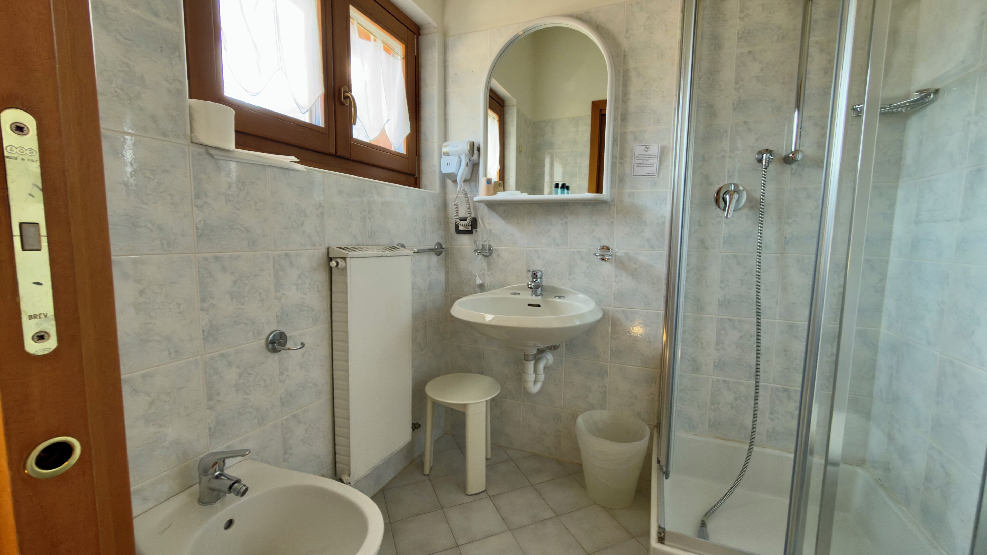 A bathroom with a shower, sink, and bidet.