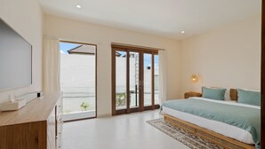 Un dormitorio moderno con una cama grande, televisión y puerta corrediza de cristal que da a un balcón.