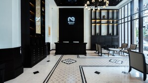 A modern hotel lobby with a reception desk, seating area, and large windows.