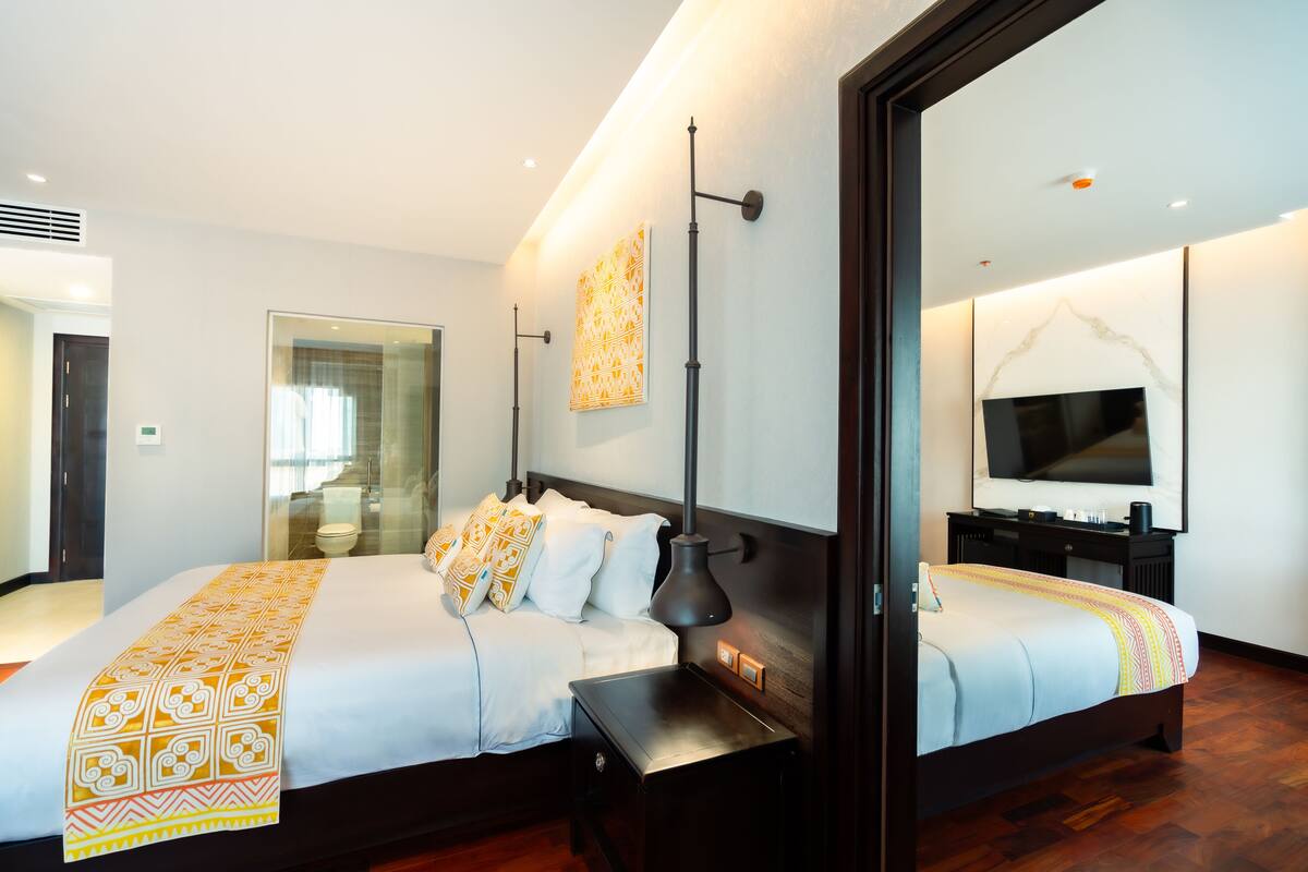 Une chambre d’hôtel moderne avec un grand lit, des tables de chevet, une télévision et un miroir.
