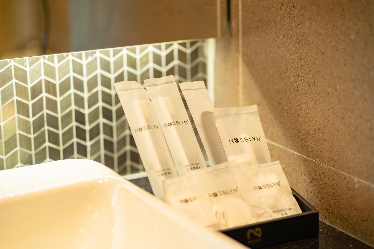 A bathroom with a white sink, a mirror, and a tray holding several bottles labeled 'ROSSLYN'.