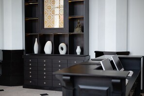 A modern room with a black desk, drawers, and a decorative panel with a Buddha statue. - Mintra Hotel (Vientiane)
