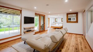 A modern bedroom with a large bed, a TV, and a sliding glass door to a balcony.