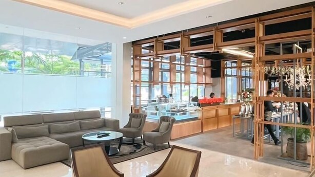 Een ruime woonkamer met een modern design, voorzien van een grote bank, een eettafel met stoelen en uitzicht op een balkon met landschap.
