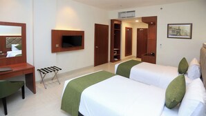 Een hotelkamer met twee bedden, een bureau, een stoel, een televisie en een kledingkast.