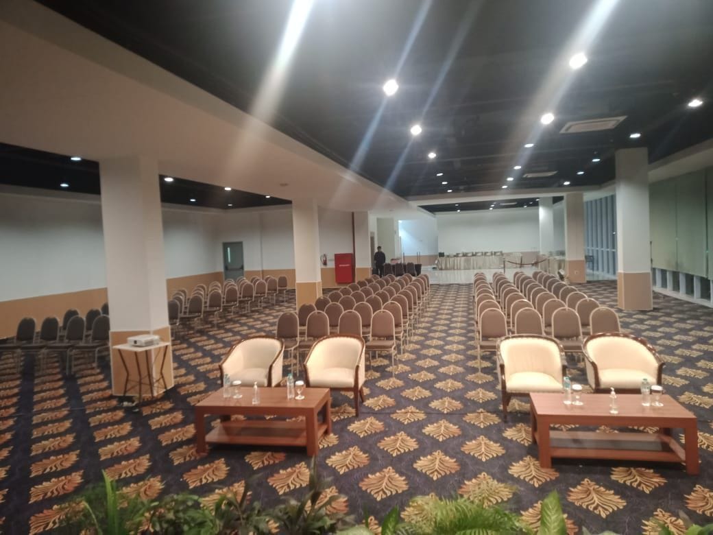 A conference room with rows of chairs, tables, and a stage.