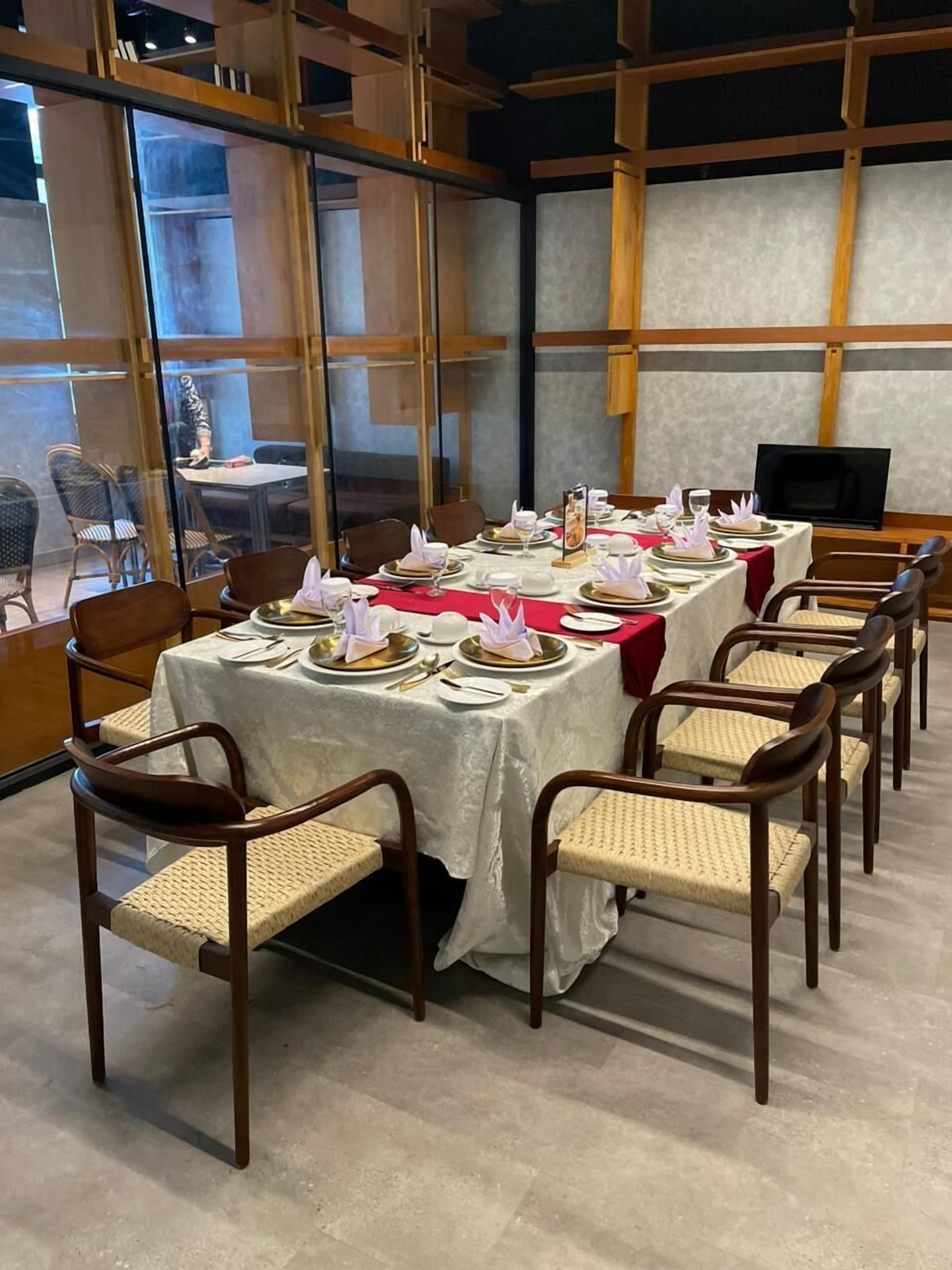 Un espace repas avec une longue table dressée pour un repas, entourée de chaises.