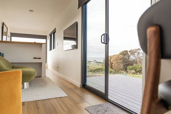 A modern interior with a sliding glass door leading to an outdoor deck, a green chair, and a minimalist design.