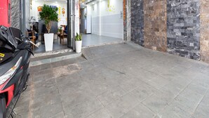A spacious lobby with a marble wall, a Honda motorcycle, and a potted plant. - Rita Hotel (Ho Chi Minh City)
