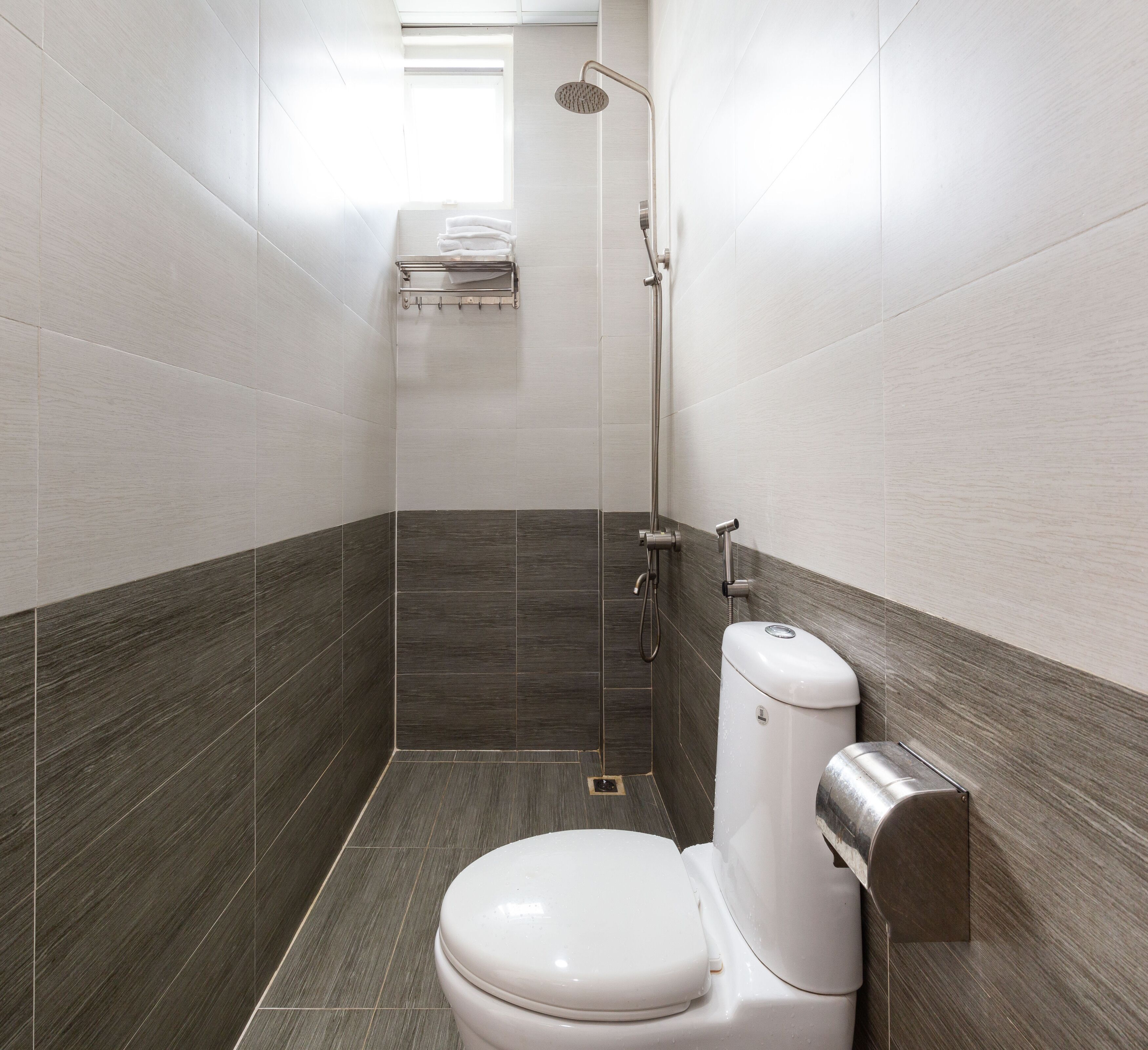 A modern bathroom with a toilet, a shower, and a towel rack.