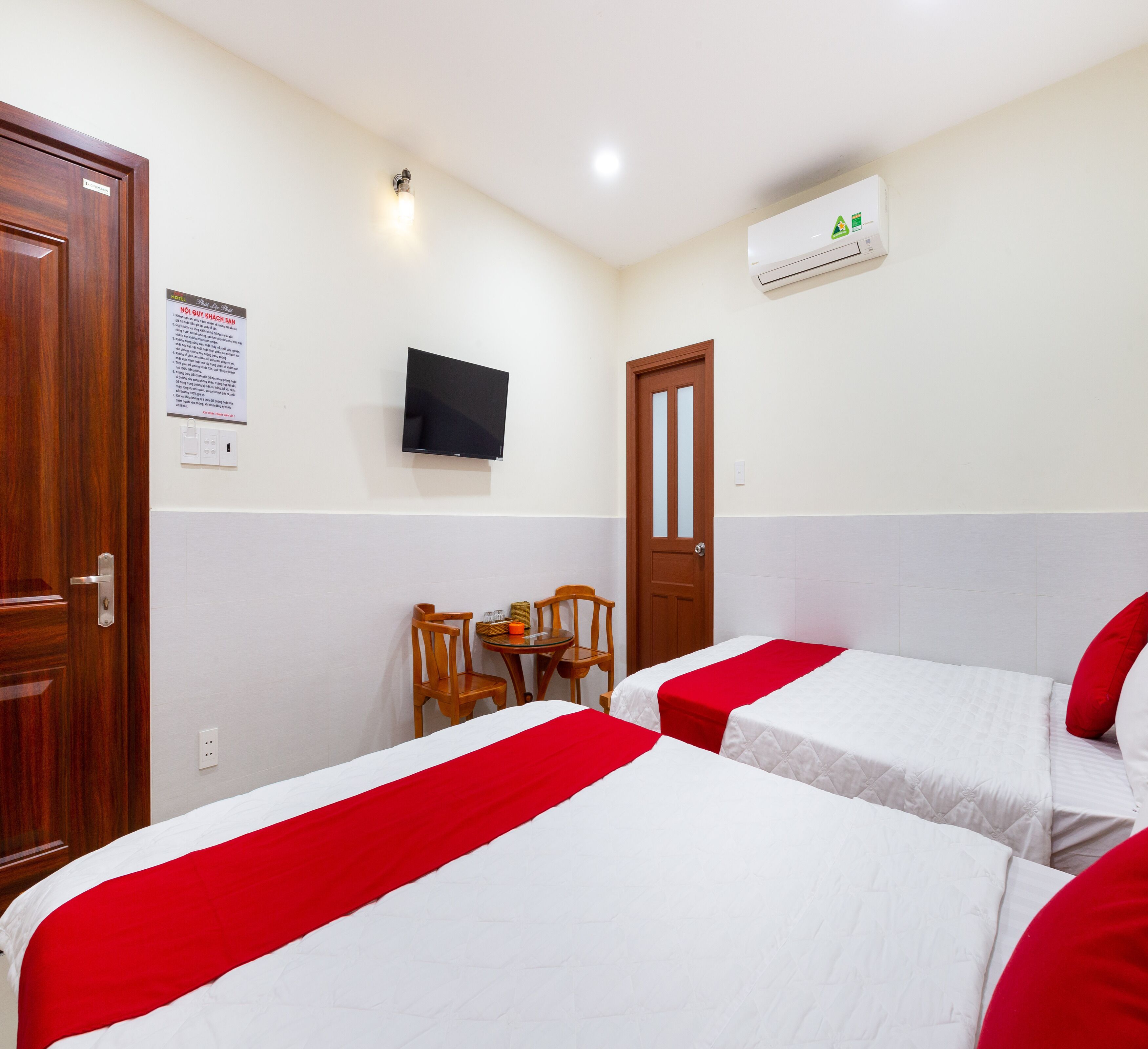 Habitación de hotel con dos camas, un escritorio, sillas, televisión y aire acondicionado.