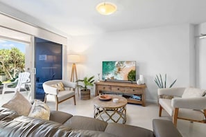A modern living room with a sofa, chairs, a TV, and a dining table.