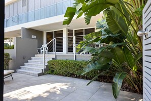 A modern building with a staircase leading to a covered entrance, surrounded by greenery. - The Sunshine Villa 2 Min walk to Village Beach (Noosa)