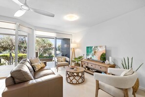 A modern living room with a sofa, armchairs, a coffee table, and a TV. - The Sunshine Villa 2 Min walk to Village Beach (Noosa)