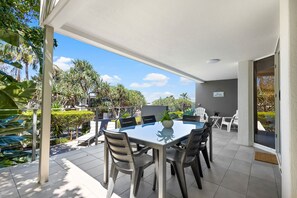 An outdoor patio with a table and chairs, surrounded by greenery and a clear sky. - The Sunshine Villa 2 Min walk to Village Beach (Noosa)