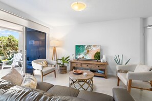 A modern living room with a sofa, chairs, a TV, and a dining table. - The Sunshine Villa 2 Min walk to Village Beach (Noosa)