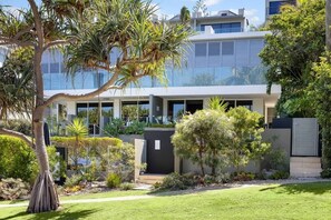 A modern building with a glass facade, surrounded by well-maintained greenery and a clear sky. - The Sunshine Villa 2 Min walk to Village Beach (Noosa)