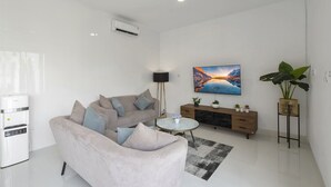 Uma sala de estar moderna com um sofá, uma mesa de centro, uma televisão e uma planta.