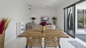 Uma sala de jantar com uma mesa de madeira, cadeiras de vime e um vaso de flores.